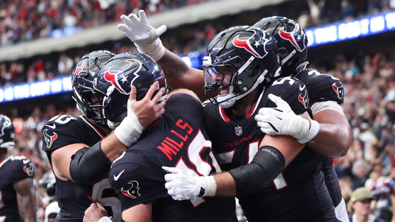 Texans quarterback Davis Mills is mobbed by teammates as his 14-yard touchdown run with 31 seconds remaining gave Houston a 30-29 lead after it had trailed Jacksonville by 19 points entering the fourt